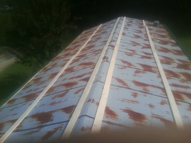 Rusted metal roof panels with new wood purlins before replacement — Storm Damage Roof Repair in West Sunbury by Roofing Brothers