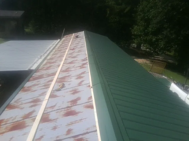 Old rusted panels beside newly installed green metal roofing — Wind Damage Roof Repair by Roofing Brothers in West Sunbury