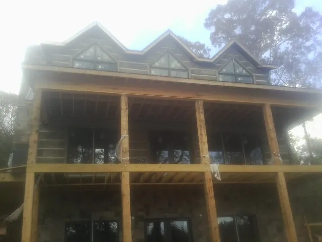 Dormers and porch framing on a large log home under construction — Roof Coating work by our crew in West Sunbury