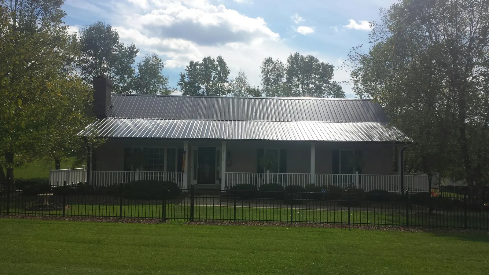 Gray metal roof on a brick ranch with a full width front porch — Gutter Guard Installation work by our crew in West Sunbury
