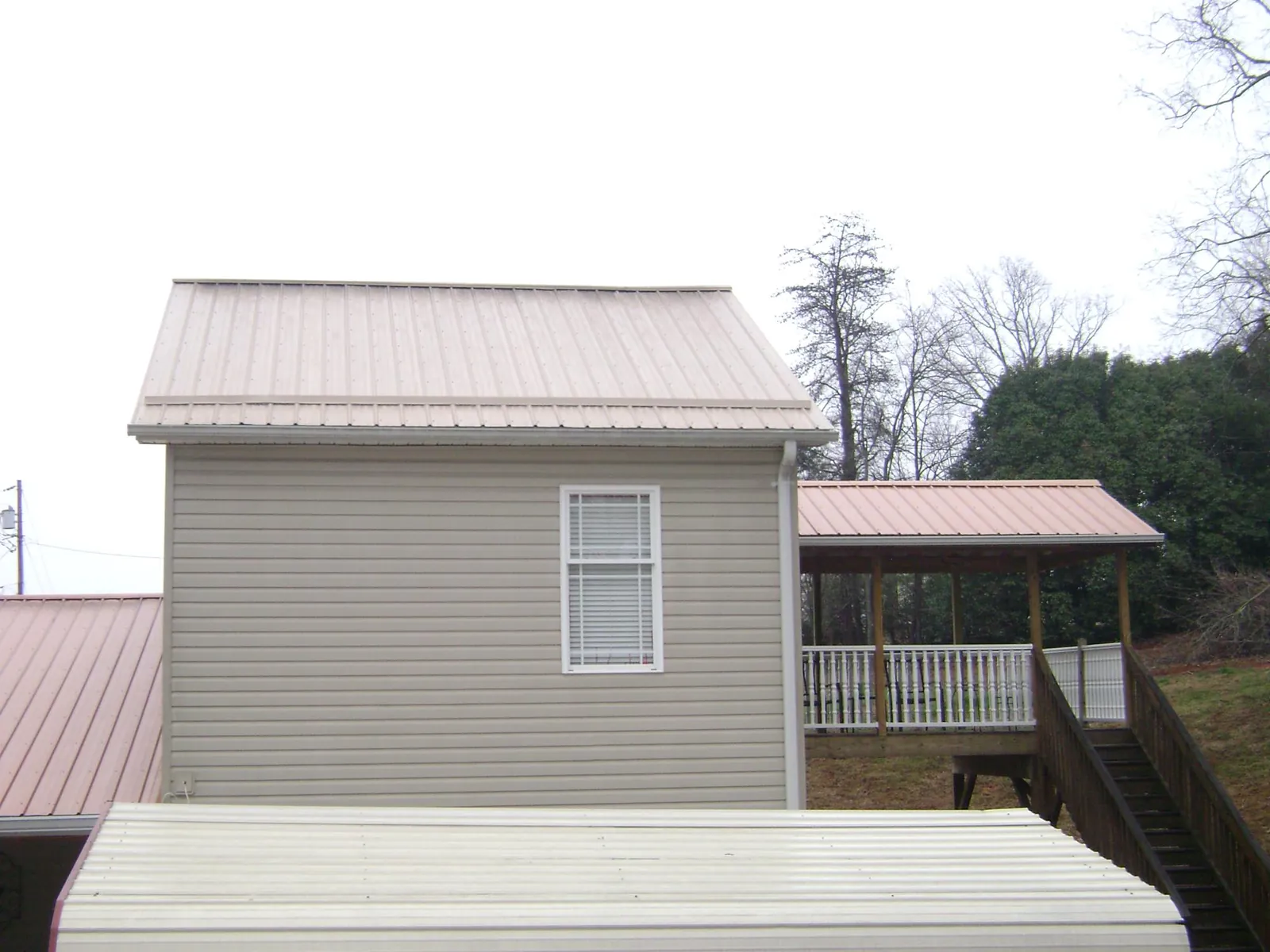 Tan metal roofs on a two story addition and attached porch, from a Roof Replacement job in West Sunbury