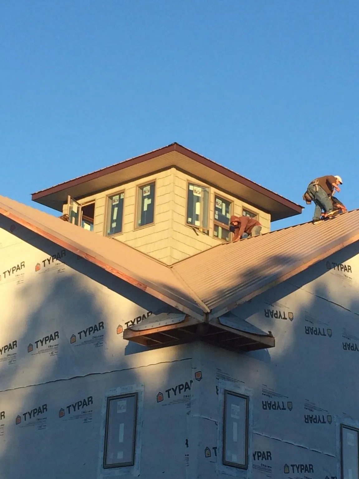 Roofers working around a rooftop cupola on a new metal roof at sunset — Roof Waterproofing in West Sunbury by Roofing Brothers